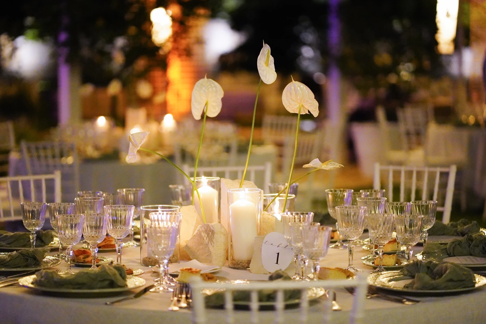 Tavola allestita con fiori bianchi e candele durante una cena aziendale