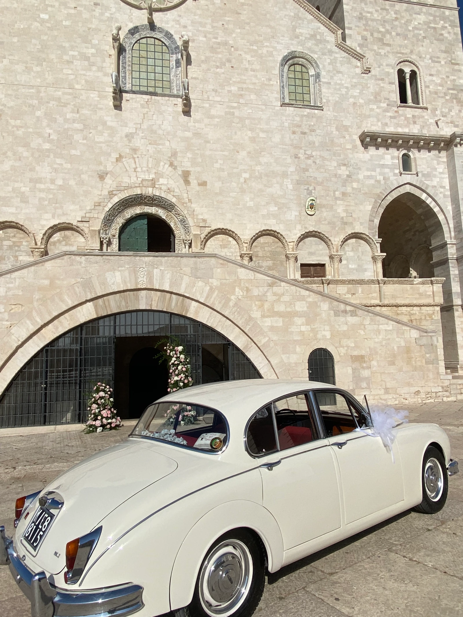 Un’auto d’epoca bianca davanti alla cattedrale, con i fiori all’ingresso