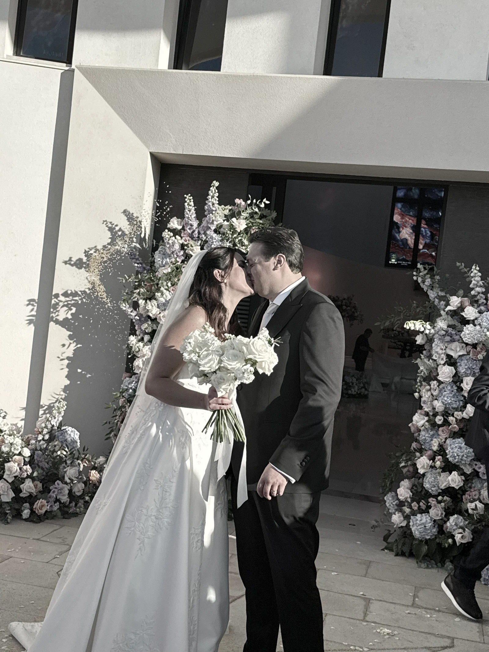 Il bacio degli sposi all’uscita della chiesa, tra archi di fiori