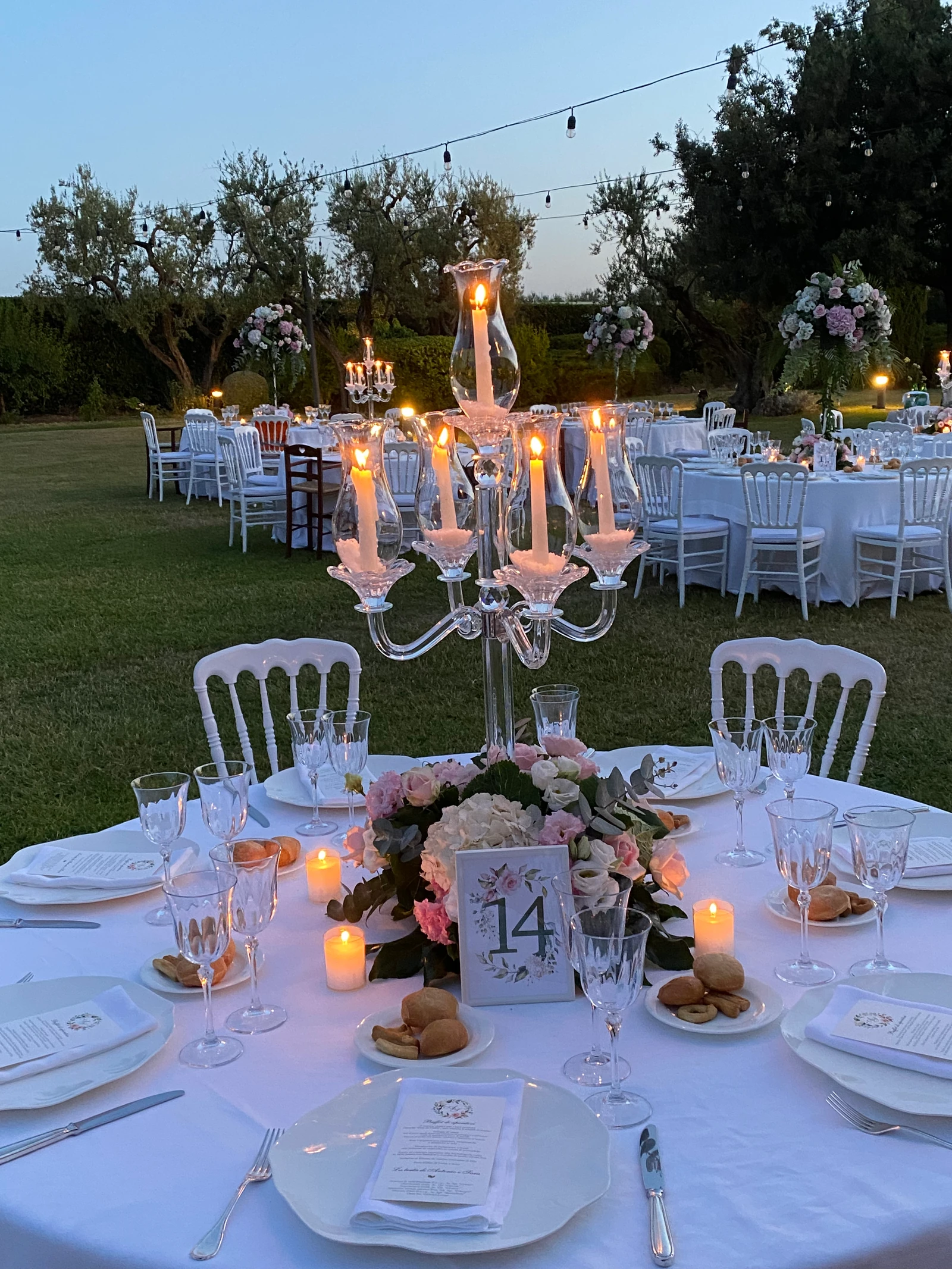 Tavola al crepuscolo con candelabro di cristallo e fiori rosa