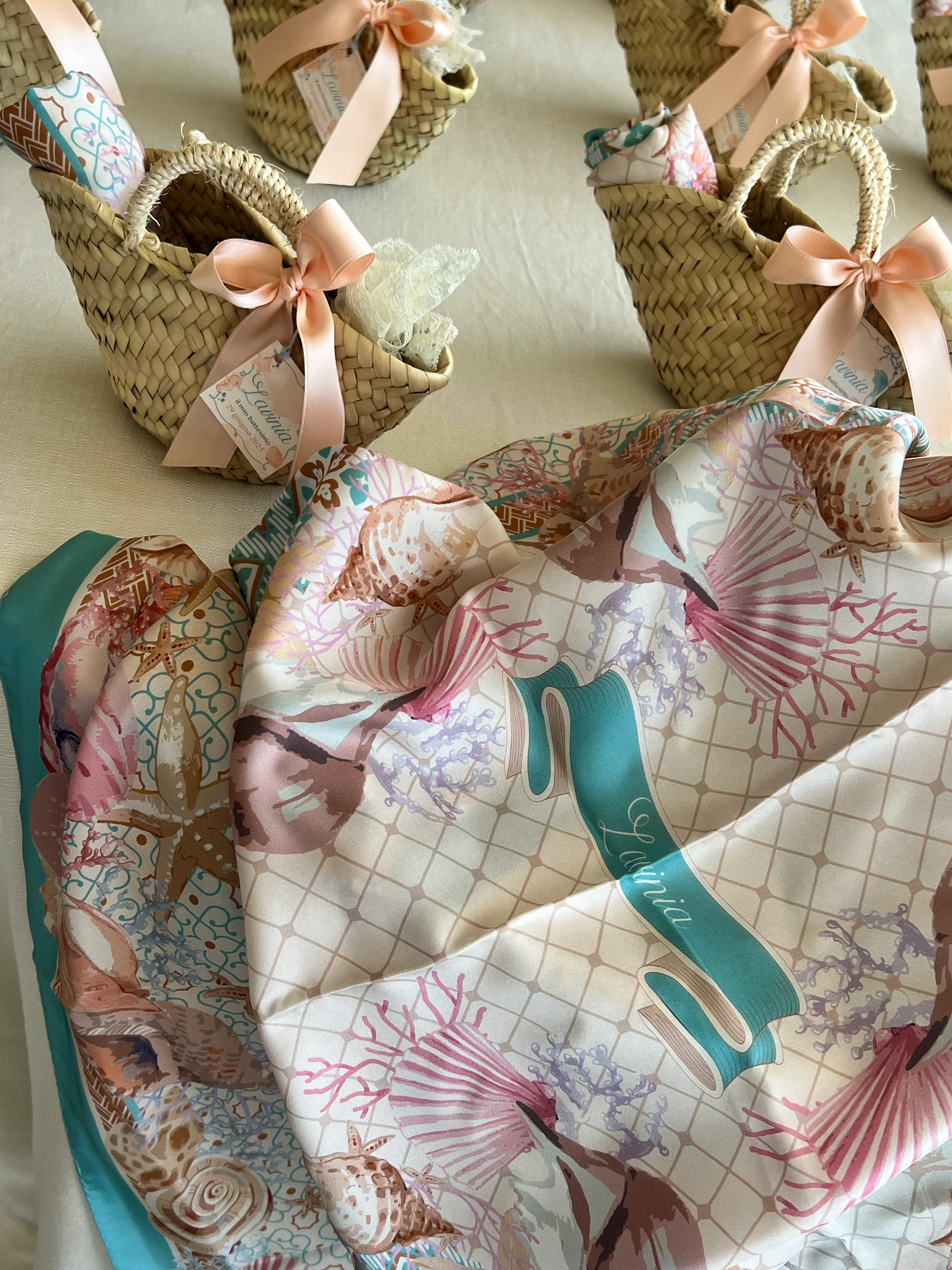 Cestini di paglia con fiocchi rosa e un foulard decorato con conchiglie