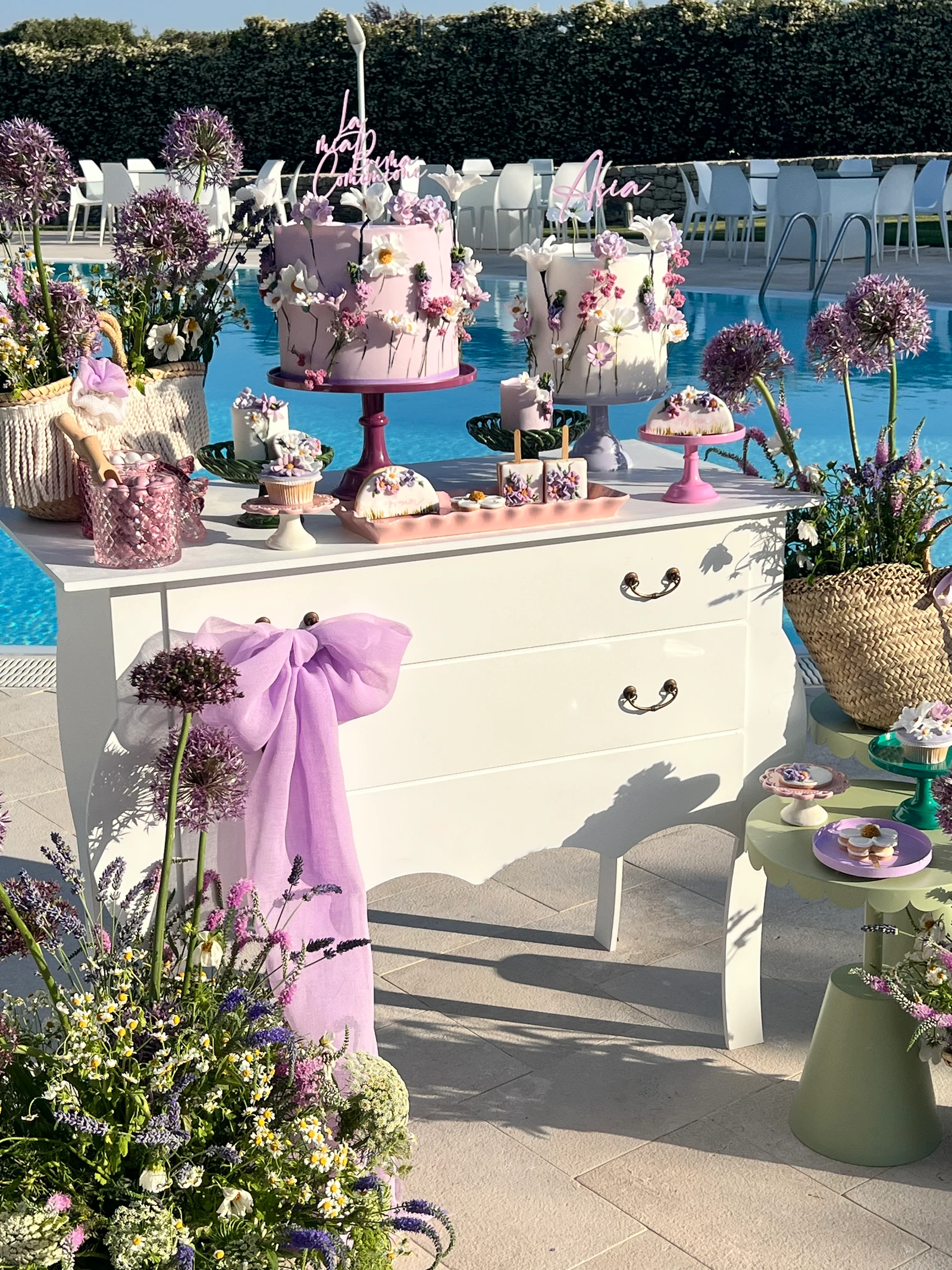 Sweet table lilla a bordo piscina, con torte e fiori di campo