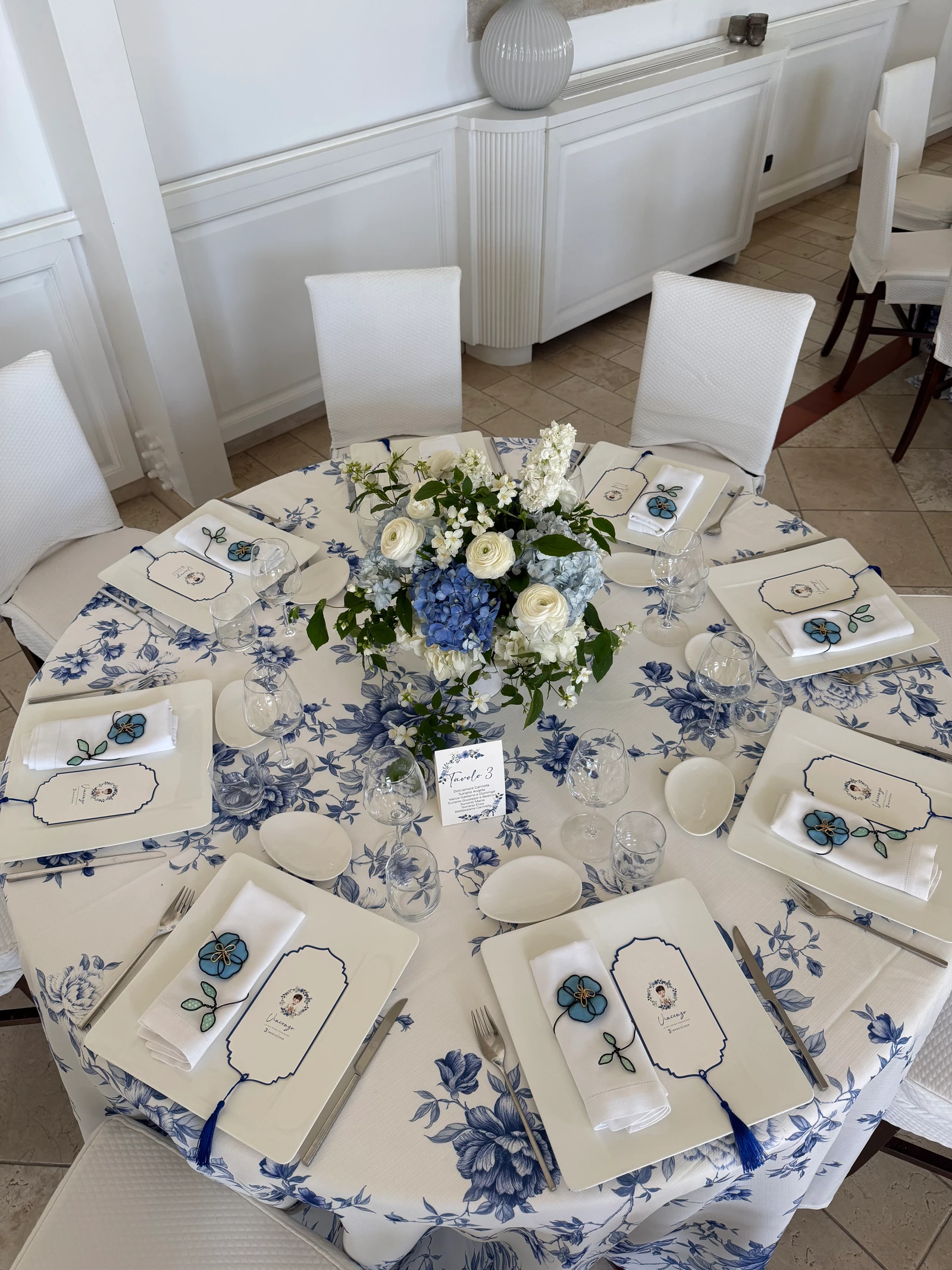 Tavola rotonda con tovaglia a fiori blu e centrotavola di ortensie