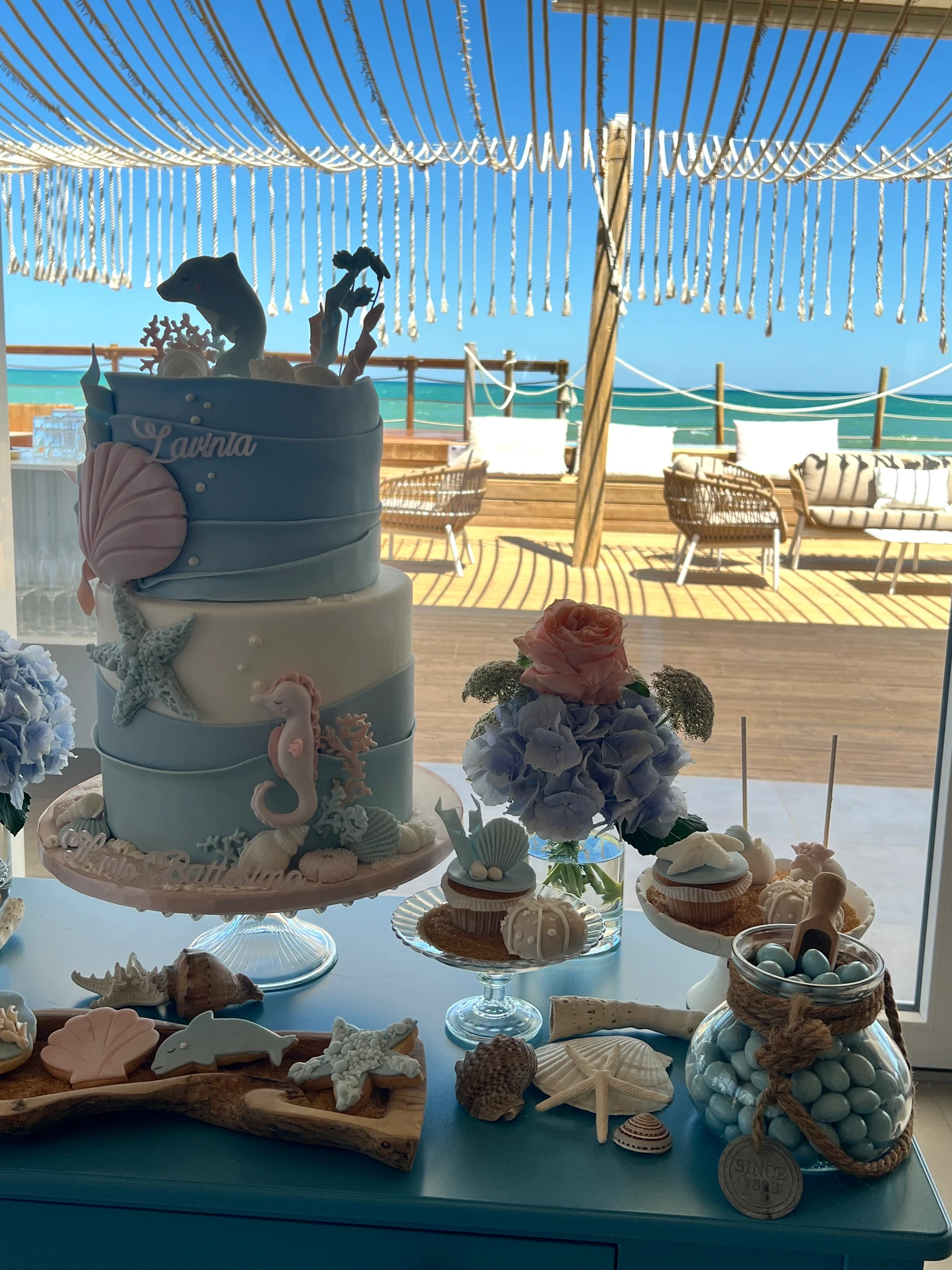 Torta a tema marino con conchiglie e dolci, davanti al mare